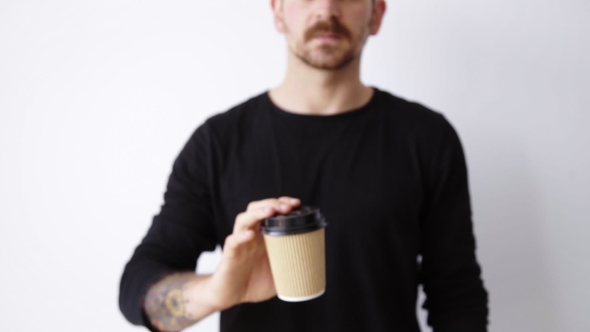 Handsome Bearded Unfocused Guy Shows Paper Cup On Camera