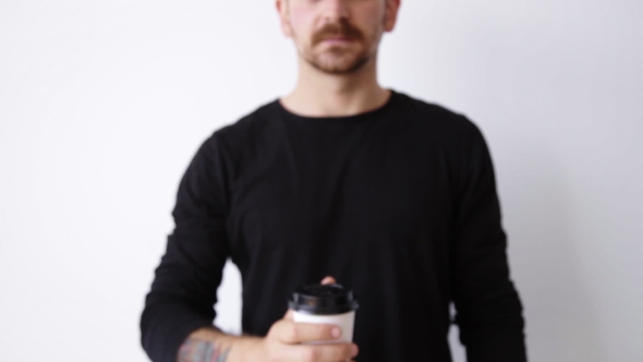 Handsome Bearded Unfocused Guy Shows Paper Cup On Camera
