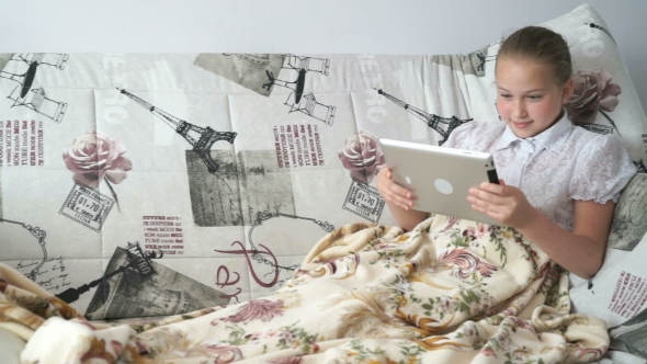 Teenager Girl Lying On a Bed With a Digital Tablet alt