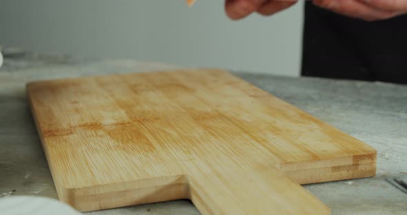 The Chef Puts a Piece of Fish on a Wooden Board for Slicing