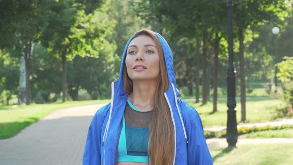 Attractive Sportswoman Taking Off the Hood Before Running in the Park