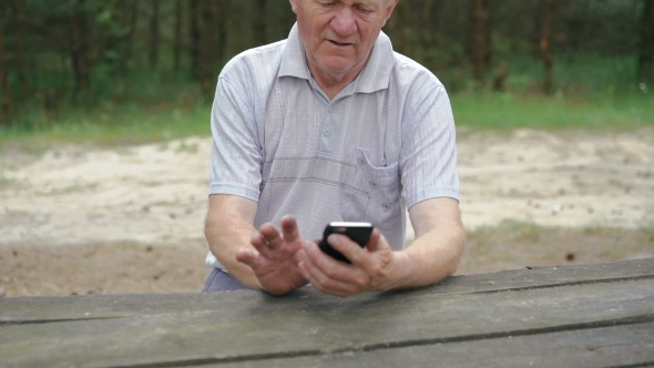 The Old Man With Wrinkles Uses The Phone In The Forest