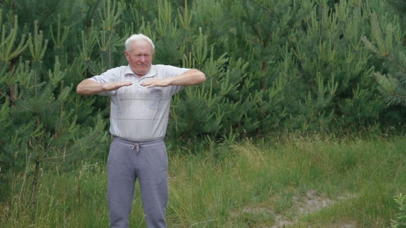 Old Man Does Morning Exercises Stretches Hands Fingers In Park