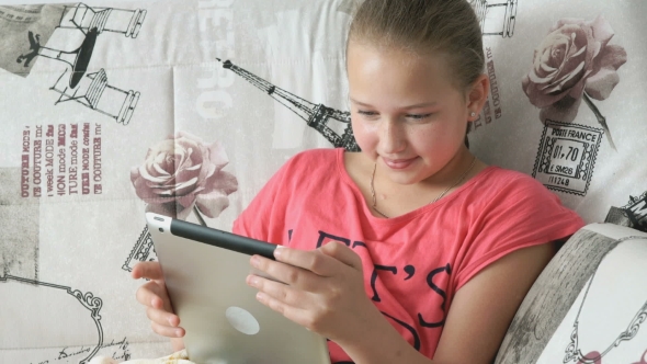 Teenager Girl Lying On a Bed With a Digital Tablet