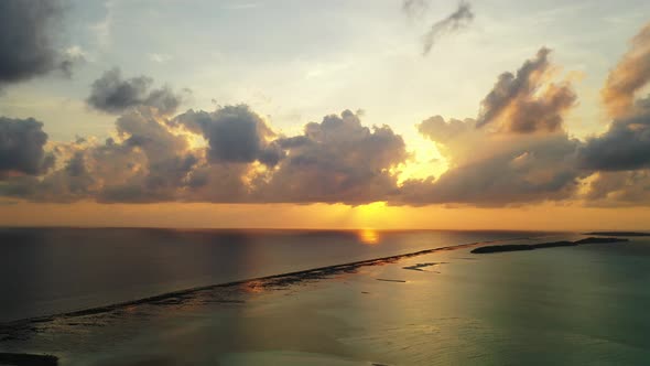 Purple clouds and golden sun rays reflecting in the calm water surface. Coral reef and open ocean ne