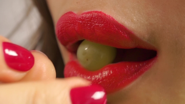 Young Woman With Red Manicure And Red Lips Eating Green Grape
