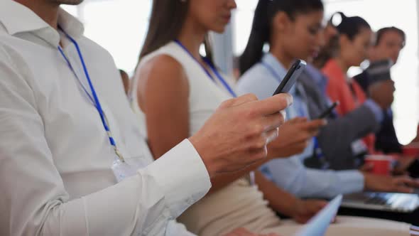 Audience at a business conference using phones and computers