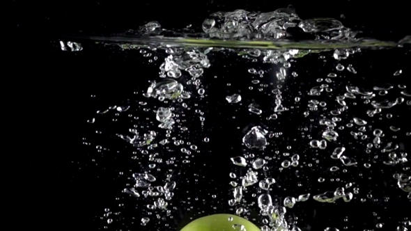 Green Apples Fall Down In Water Against Black Background