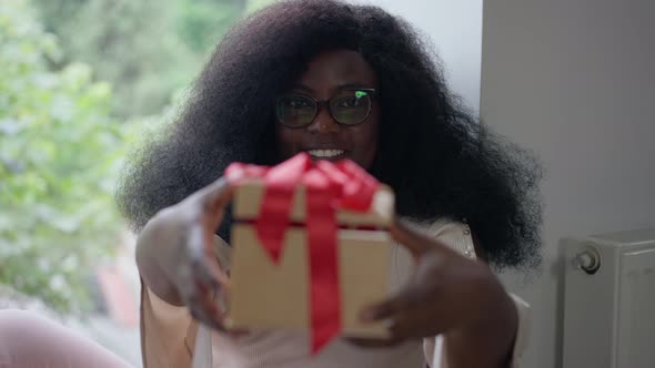 Rack Focus From Smiling African American Woman to Gift Box Stretched to Camera