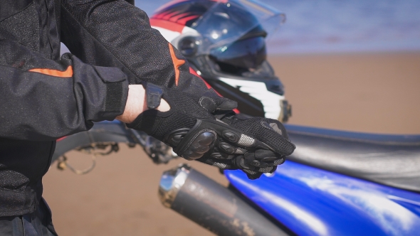 Biker In The Street Next To His Bike, Takes Off His Gloves.