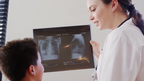 Female physiotherapist showing x-ray report to boy patient 4k