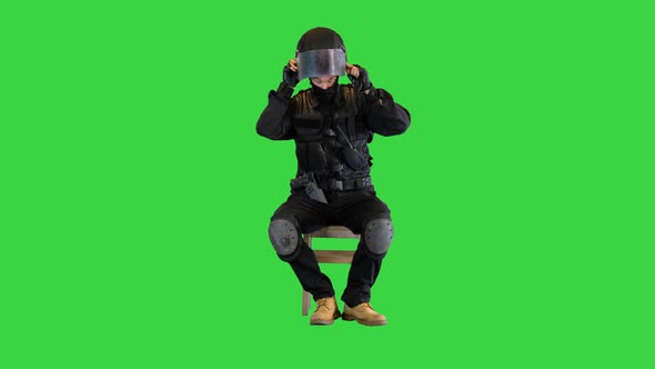 Riot Policeman Sitting and Putting on Helmet on a Green Screen Chroma Key