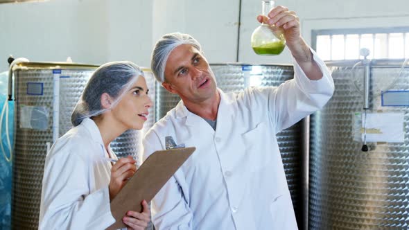 Technicians writing on clipboard while examining olive oil 4k