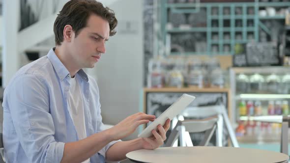 Attractive Young Man Using Tablet in Cafe