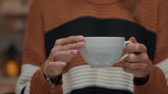 Close Up of Tea Cup Held By Young Woman at Home