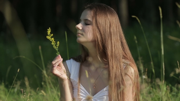 Genuine Woman In Meadow Sniffing Flower