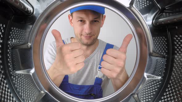 Washing machine repair worker looks inside mababan and shows class.