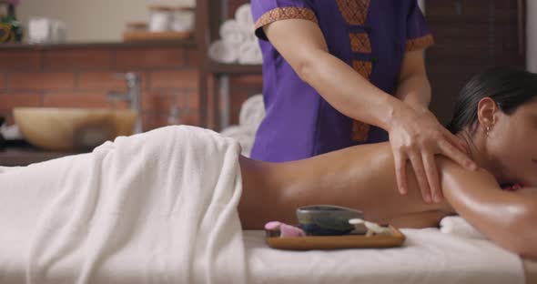 Young Attractive Brunette Woman Lying on Massage Table in Spa Center and Enjoying Rejuvenating Back