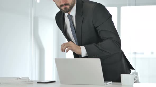 Businessman Leaving Office After Closing Laptop at Work