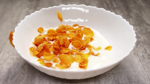 Bowl with Milk and Thrown Yellow Cornflakes in It in Slow Motion