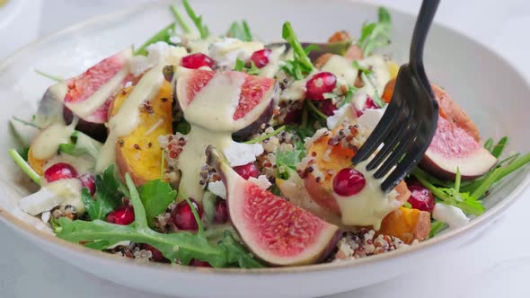 Eating Warm Autumn Quinoa Salad with Baked Vegetables Figs Feta Pomegranate and Dressing