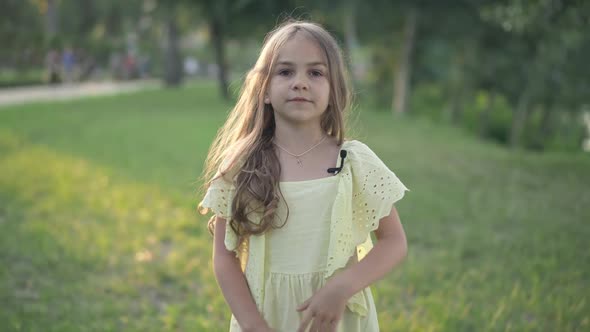 Confident Pretty Caucasian Girl in Yellow Dress with Lapel Microphone Talking Looking at Camera