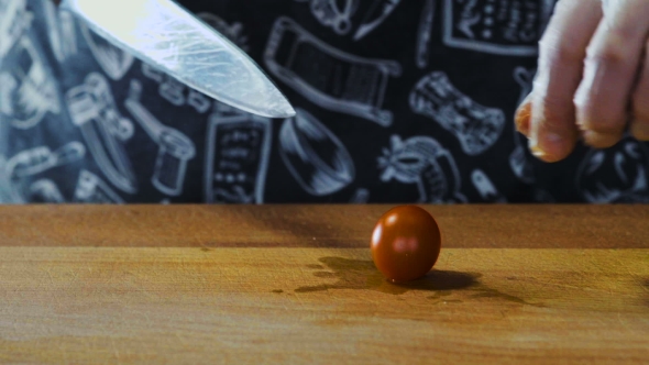 Chef Cuts Cherry Tomato On Wooden Board
