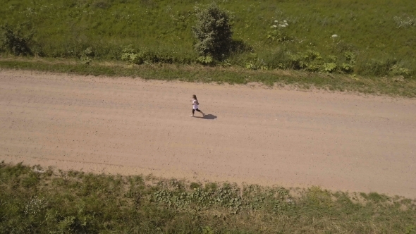 Girl Runs On The Road In a field.Aerial View.