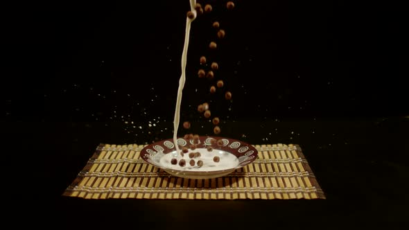 Pouring milk and chocolate cereal balls on a plate, Ultra Slow Motion