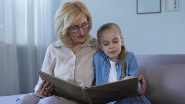 Blond Grandkid Reading Fairytale With Her Grandmother at Home, Togetherness