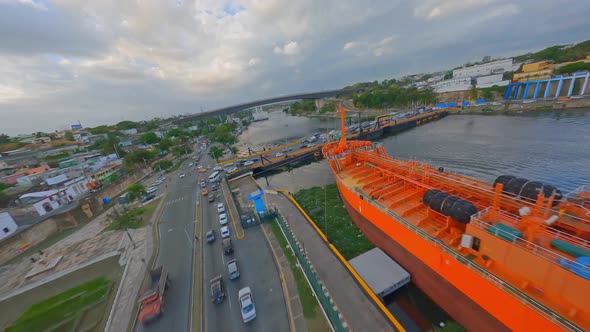 Aerial fpv flight showing cars on bridge crossing Port of Don Diego with docking industrial ships