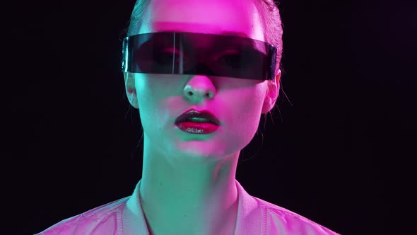Portrait of teenage girl in cyberpunk style. Young woman posing in futuristic sunglasses.