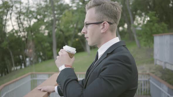 Portrait of Young Ambitious Successful Businessman Standing on the Terrace Drinking Coffee