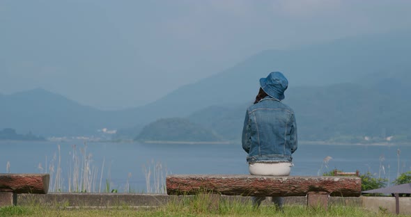 Woman look at the lake and sit on the bench