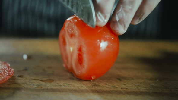 Chef Slicing Tomato On Wooden Board