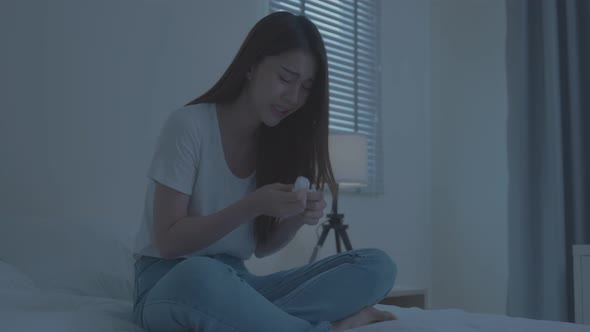 Asian beautiful depression girl crying in tears sit on bed in bedroom.