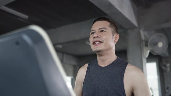 4K Portrait of Asian sportsman in sportswear jogging workout exercise on treadmill at fitness gym.