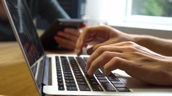 Male hands typing on laptop keyboard in cafe