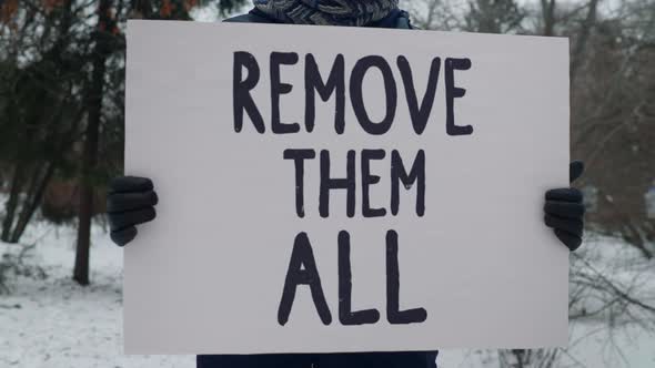 Person is Holding a sign that says Remove them All.Person Expressing Frustration