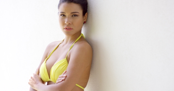 Serious Woman In Bikini With Folded Arms Near Wall