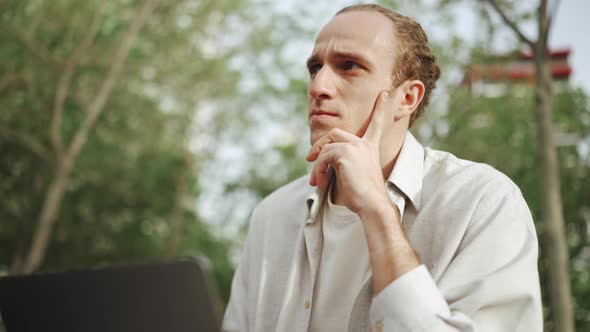 Handsome curly-haired man working on laptop