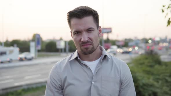 A Young Caucasian Man Shows a Thumb Down to the Camera and Shakes His Head in an Urban Area