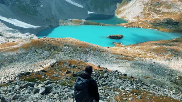 Traveler on the background of a huge lake in the mountains with blue water