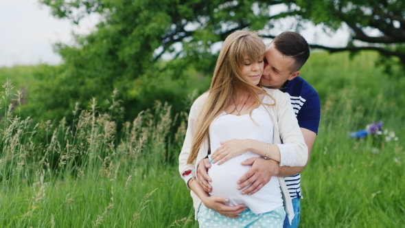 Future Parents. A Pregnant Woman With Her Husband Hugging In The Park