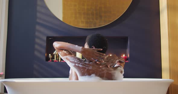 Happy african american woman taking bath in bathroom