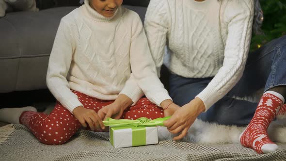 Portrait of African American Mom and Her Little Daughter Tying a Bow on a Gift Box