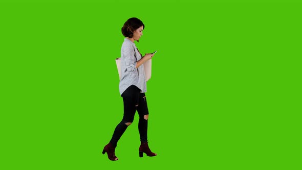 Using an app happily while walking by a casual woman over green screen. 4K