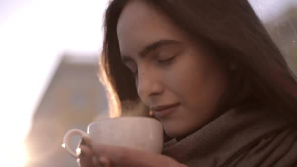 Portrait Closeup of Dreaming Young Woman Drinking Hot Coffee or Tea From Cup While Resting in City