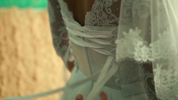 Bridesmaid Tying Bow On Wedding Dress