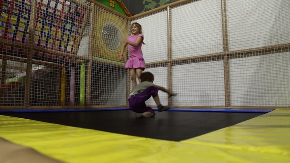 A Girl and a Boy are Jumping on a Trampoline